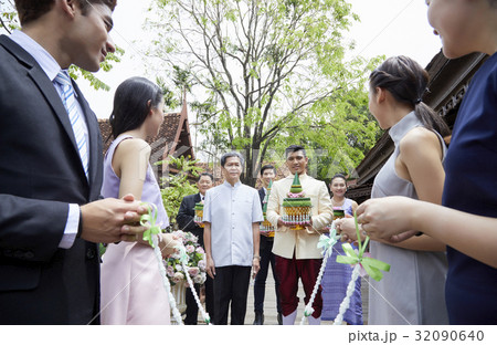 the groom is holding gift while other people are waiting, looking at him 32090640