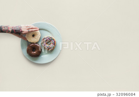 Hand with tattoo reaching for donut Hand with tattoo reaching for donut 32096084