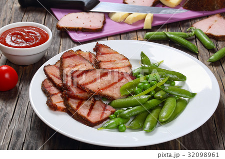 grilled slices of meat,  green pea pods 32098961