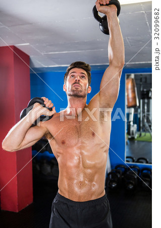 Shirtless athlete exercising with kettlebells Shirtless athlete exercising with kettlebells 32099682