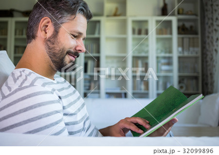 Father looking at photo album in living room Father looking at photo album in living room 32099896