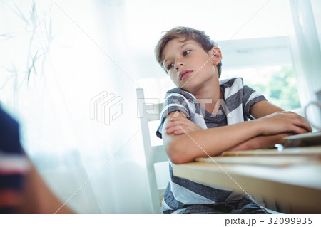 Thoughtful boy sitting on chair 32099935