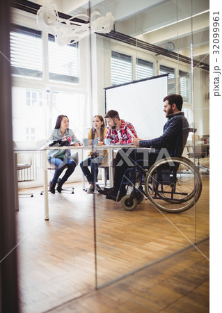 Businessman on wheelchair with photo editors in meeting room Businessman on wheelchair with photo editors in meeting room 32099961