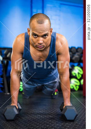 Portrait of serious male athlete doing push-ups with dumbbells Portrait of serious male athlete doing push-ups with dumbbells 32100006