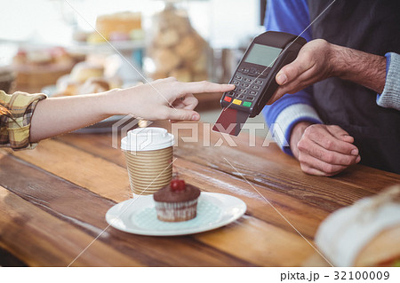 Customer entering pin number into machine at counter Customer entering pin number into machine at counter 32100009