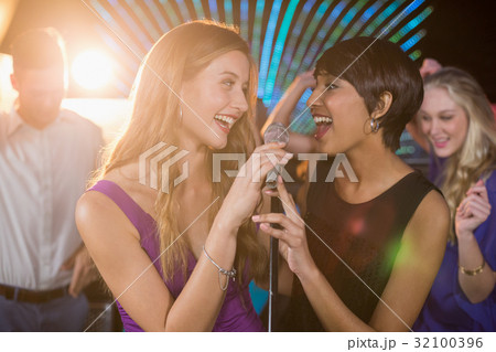 Two beautiful women singing song together Two beautiful women singing song together 32100396