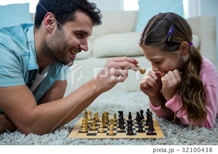 Father and daughter playing chess in the living room 32100438
