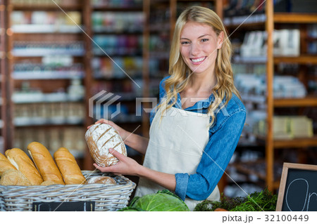 Smiling staff holding bread in organic section 32100449