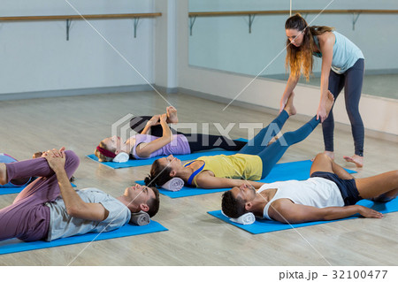 Yoga instructor helping student with a correct pose Yoga instructor helping student with a correct pose 32100477