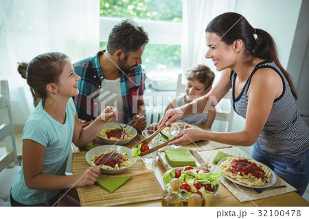 Smiling woman serving meal to her family Smiling woman serving meal to her family 32100478
