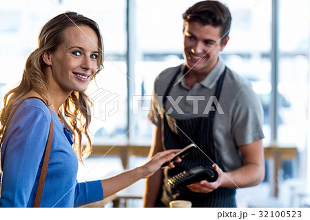 Woman paying bill through smartphone using NFC technology 32100523