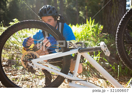 Male mountain biker fixing his bike chain Male mountain biker fixing his bike chain 32100607