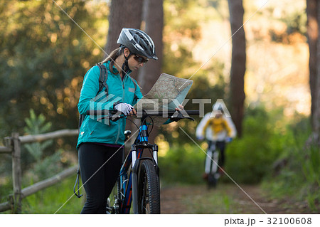 Female biker looking at a map with mountain bike Female biker looking at a map with mountain bike 32100608