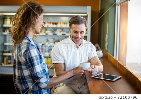 Smiling woman offering a cup of coffee to man Smiling woman offering a cup of coffee to man 32100796
