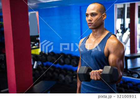 Determined man exercising with dumbbells 32100931