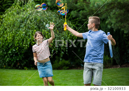 Kids playing with bubbles in the park Kids playing with bubbles in the park 32100933