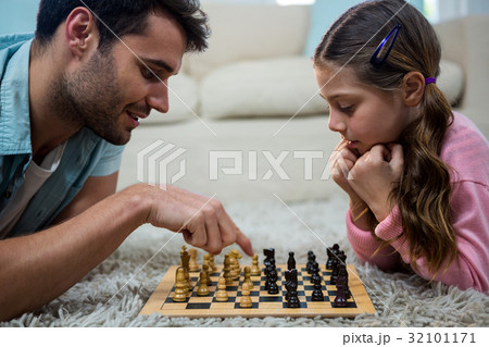 Father and daughter playing chess in the living room 32101171