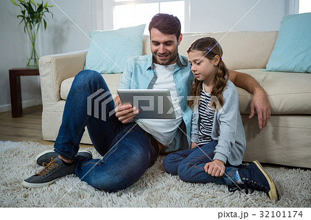 Father and daughter using digital tablet in the living room 32101174