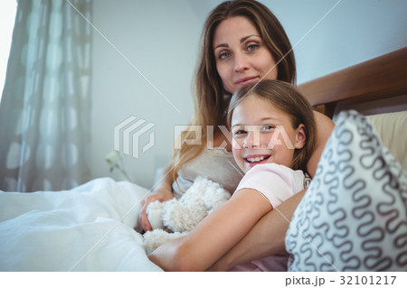 Mother lying with daughter on bed 32101217