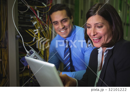 Technicians using digital tablet while analyzing server Technicians using digital tablet while analyzing server 32101222