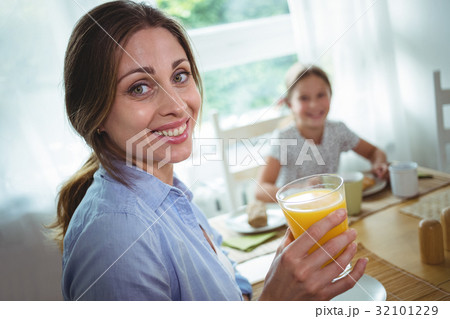 Woman having a glass of orange juice at home 32101229