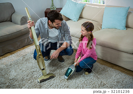 Daughter helping father to clean carpet with a vacuum cleaner Daughter helping father to clean carpet with a vacuum cleaner 32101236