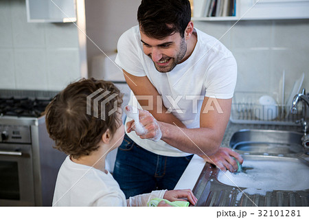 Son helping father in washing utensils 32101281