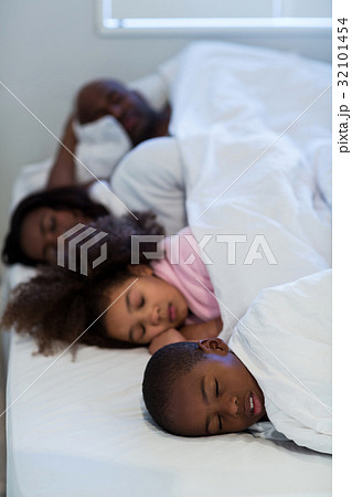 Family sleeping on bed 32101454