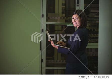 Technician using laptop while analyzing server Technician using laptop while analyzing server 32101619