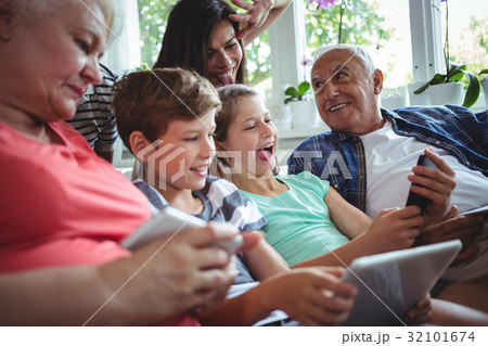 Happy multi-generation family sitting together in living room 32101674