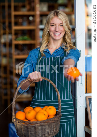 Smiling female staff holding basket of fruit in organic section Smiling female staff holding basket of fruit in organic section 32101681