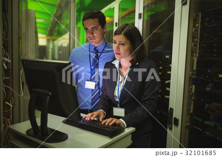 Technicians working on personal computer while analyzing server 32101685