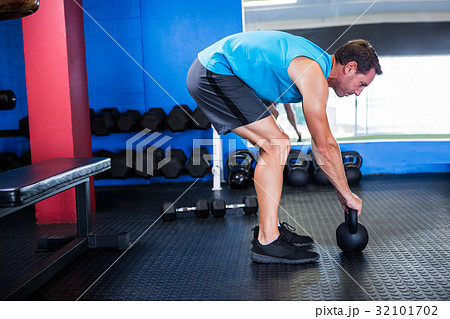 Side view of athlete with kettlebell in gym Side view of athlete with kettlebell in gym 32101702