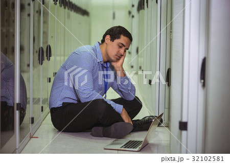 Stressed technician sitting on floor and looking at laptop Stressed technician sitting on floor and looking at laptop 32102581