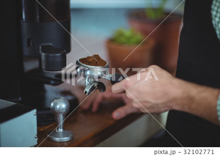 Waiter holding portafilter filled with ground coffee 32102771