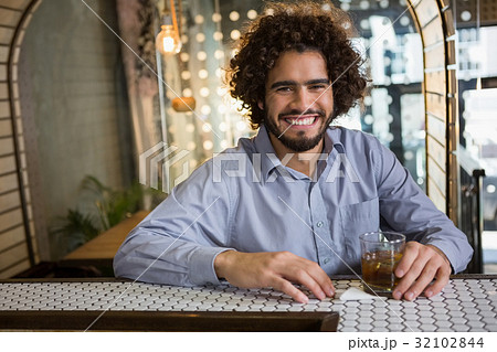 Man sitting on bar counter with glass of whisky 32102844