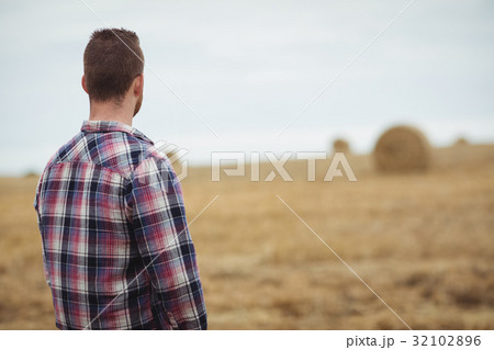 Rear view of farmer standing in field 32102896
