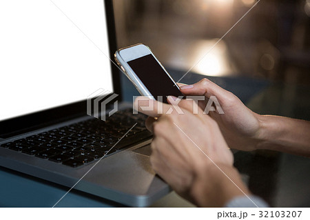Woman text messaging on mobile phone in the office Woman text messaging on mobile phone in the office 32103207