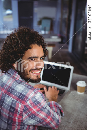 Portrait of man smiling while using laptop Portrait of man smiling while using laptop 32103696
