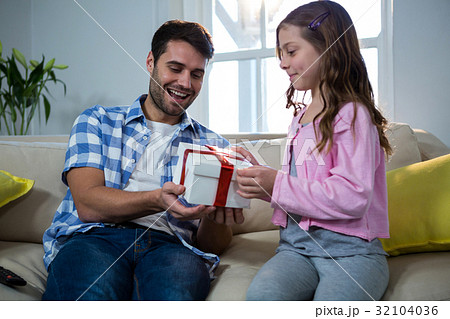 Father giving gift to daughter in the living room Father giving gift to daughter in the living room 32104036