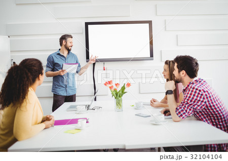 Colleagues listening to executive in meeting at creative office Colleagues listening to executive in meeting at creative office 32104104