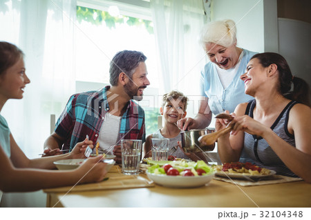 Elderly woman serving meal to her family 32104348