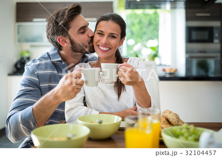 Man kissing on woman cheeks while having breakfast 32104457