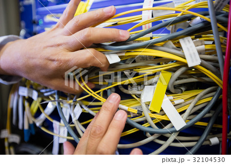 Technician checking cables in a rack mounted server Technician checking cables in a rack mounted server 32104530