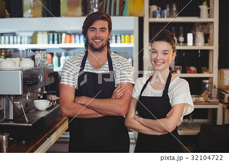 Waiter and waitress standing with arms crossed in cafe 32104722