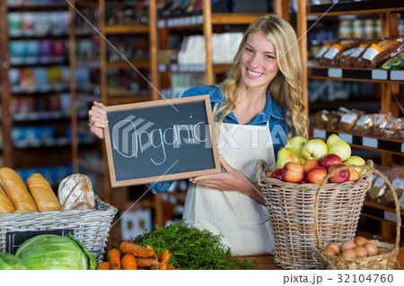 Smiling staff holding organic sign board in organic section Smiling staff holding organic sign board in organic section 32104760