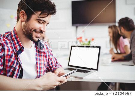 Happy executive texting in meeting at creative office Happy executive texting in meeting at creative office 32104967