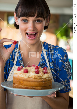 Excited waitress holding a cake and showing a cherry 32105334