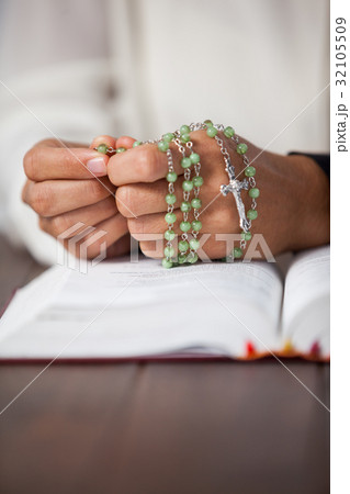 Praying hands of woman with a rosary on bible Praying hands of woman with a rosary on bible 32105509