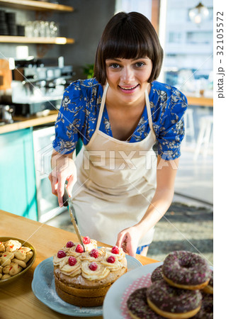Smiling waitress cutting a cake in the coffee shop 32105572